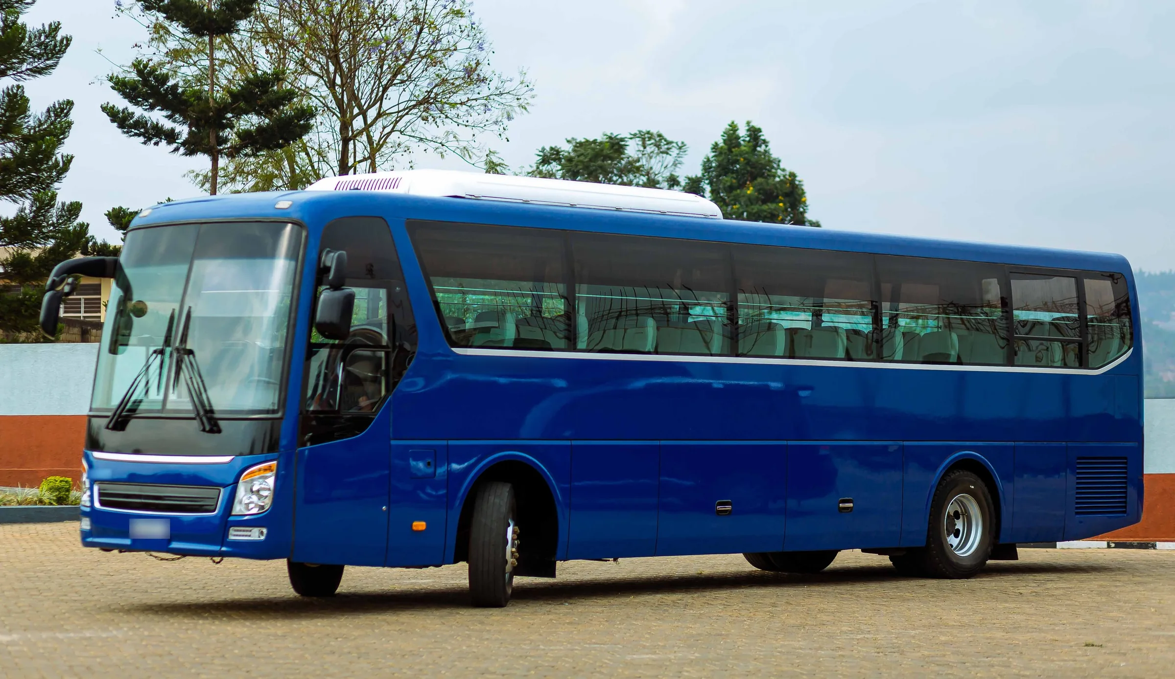 A full-size blue coach bus parked on a paved lot