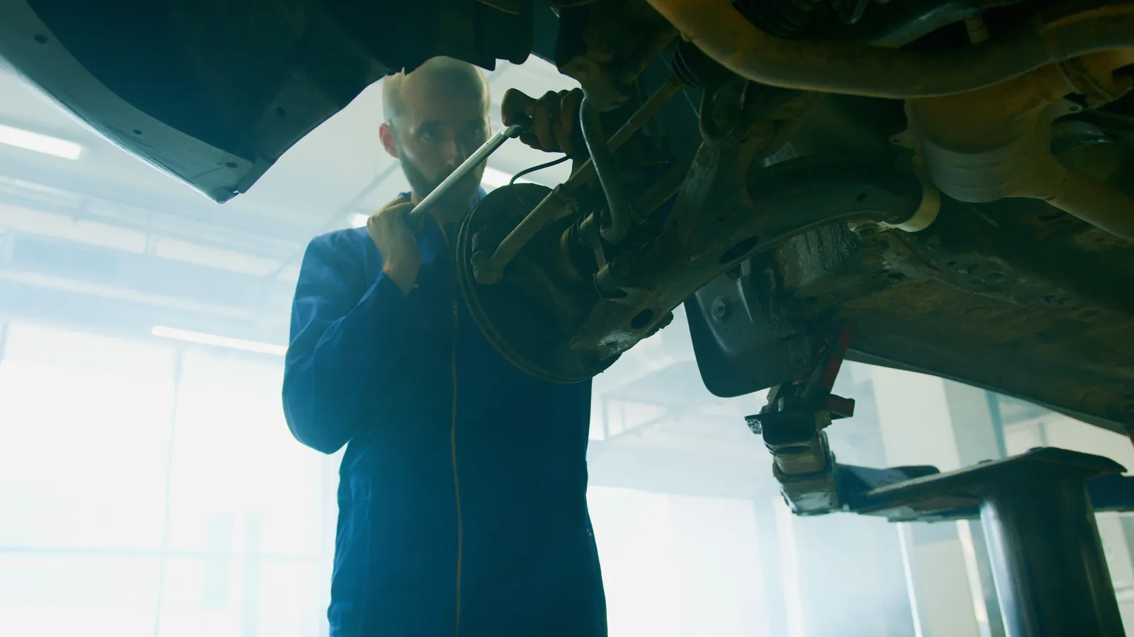 A technician working on a driveline joint from under a vehicle