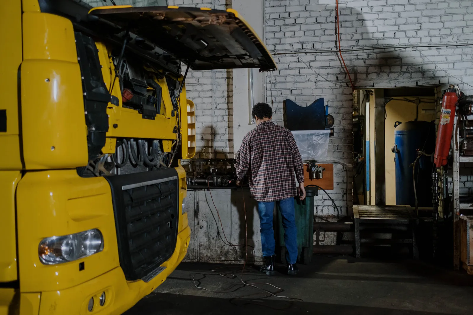 A truck with the front open in the shop and a technician at the bench