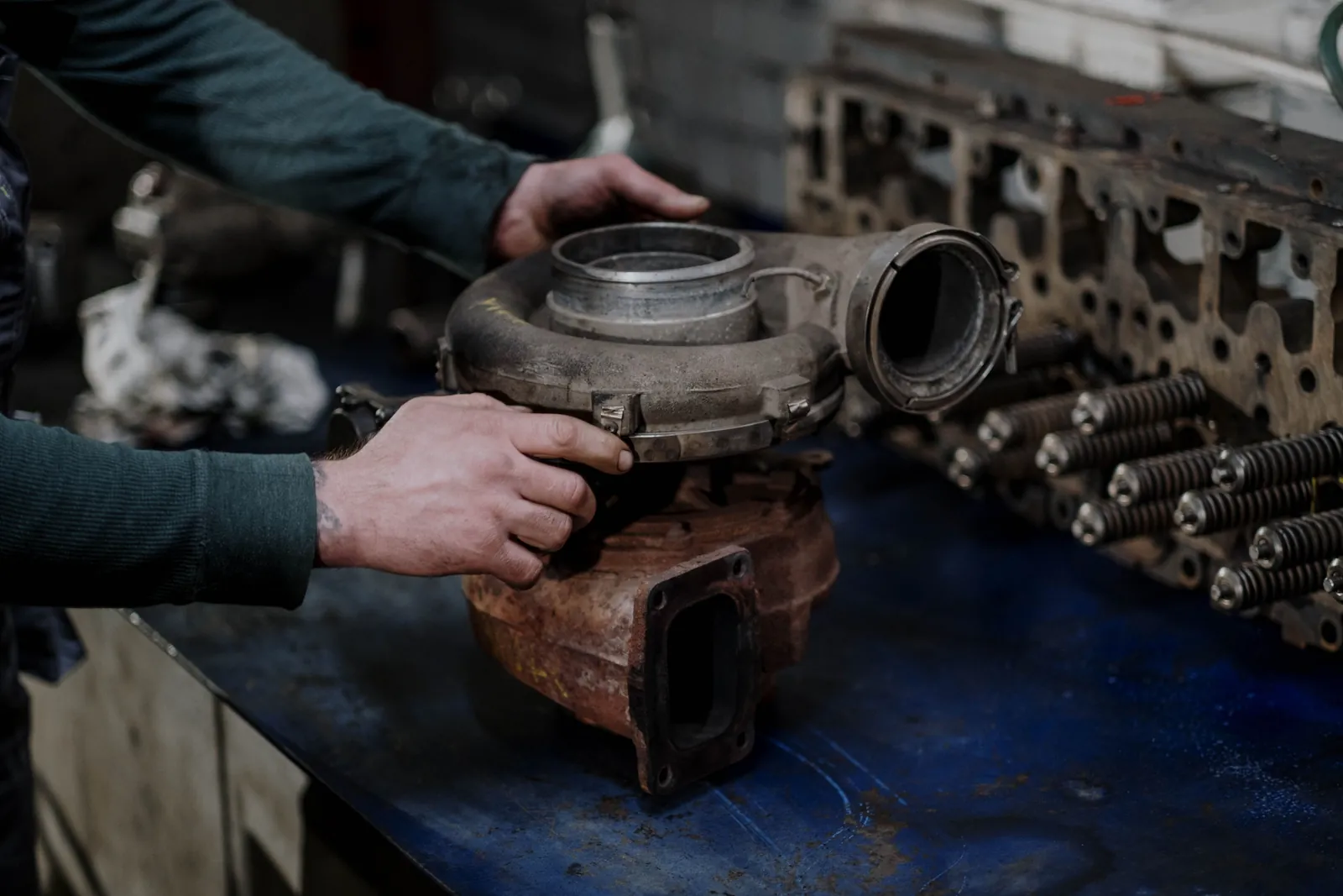 A turbocharger on the bench beside a cylinder head