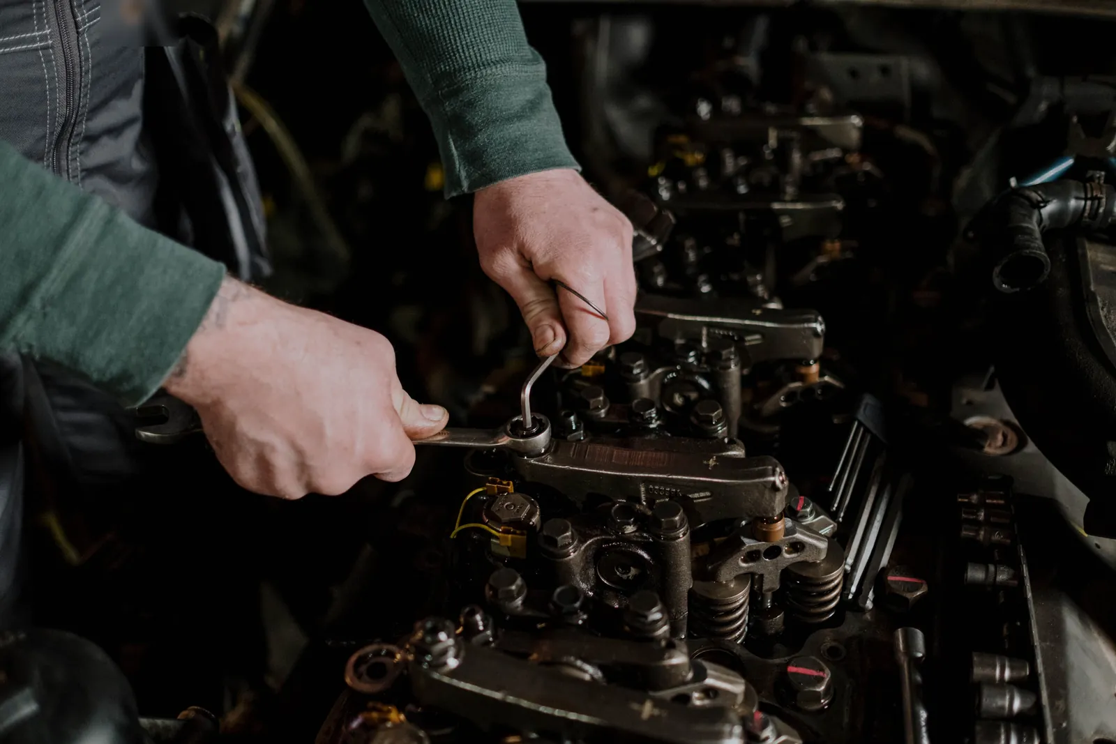 A technician's hands adjusting rocker arms on a diesel engine