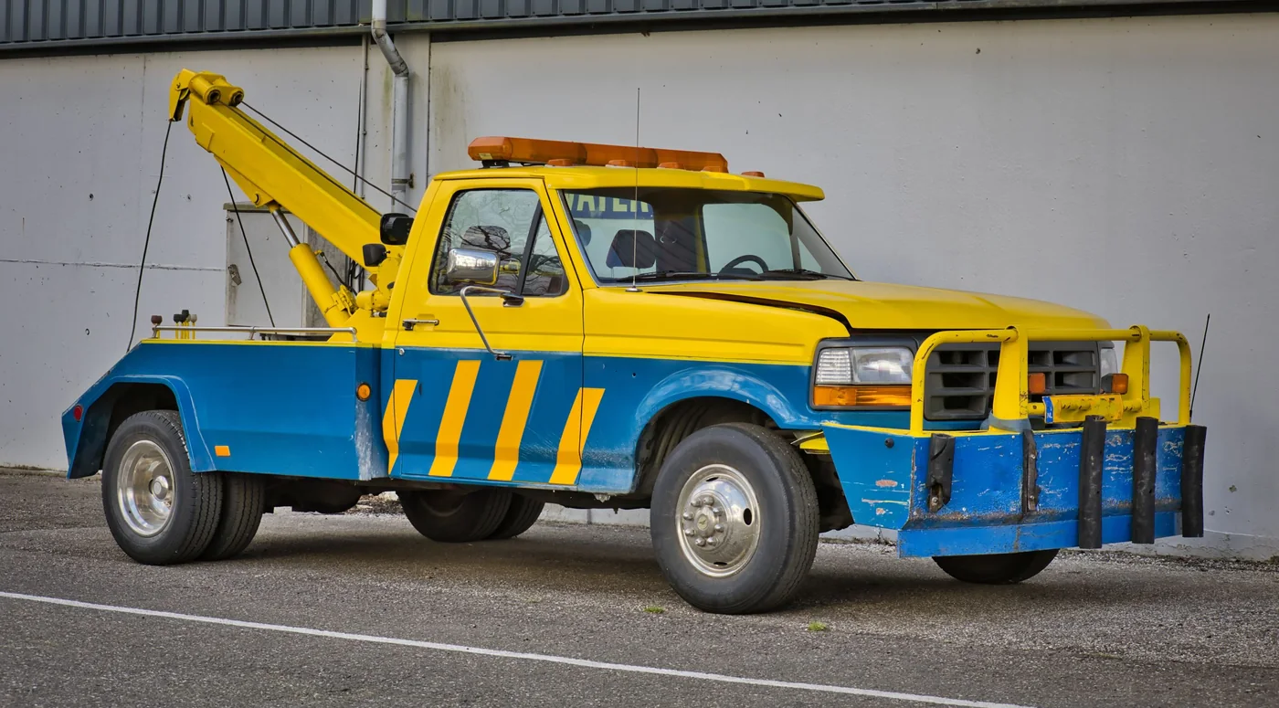 A wrecker with its boom raised, parked beside a building