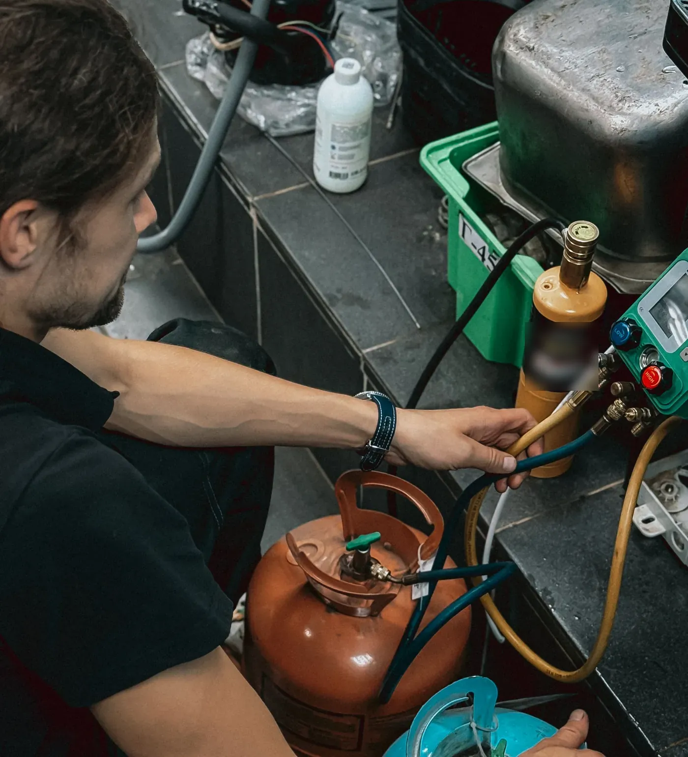 A technician working with refrigerant tanks and gauges