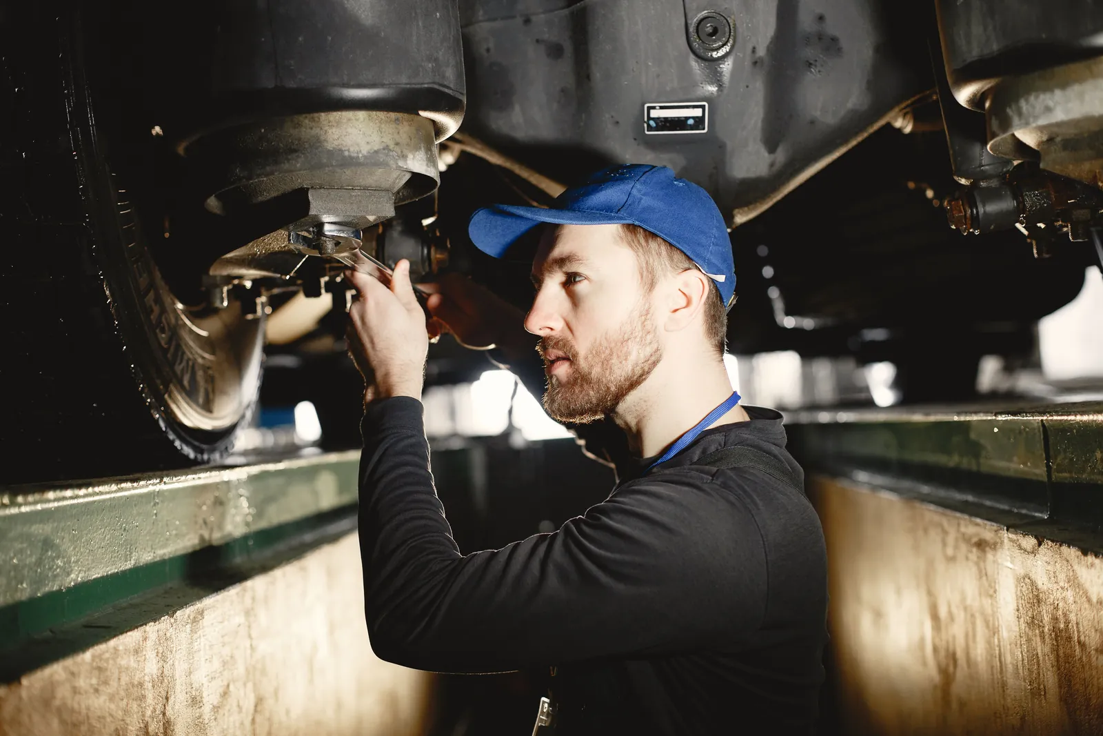 A technician working at the underside of a truck from the pit