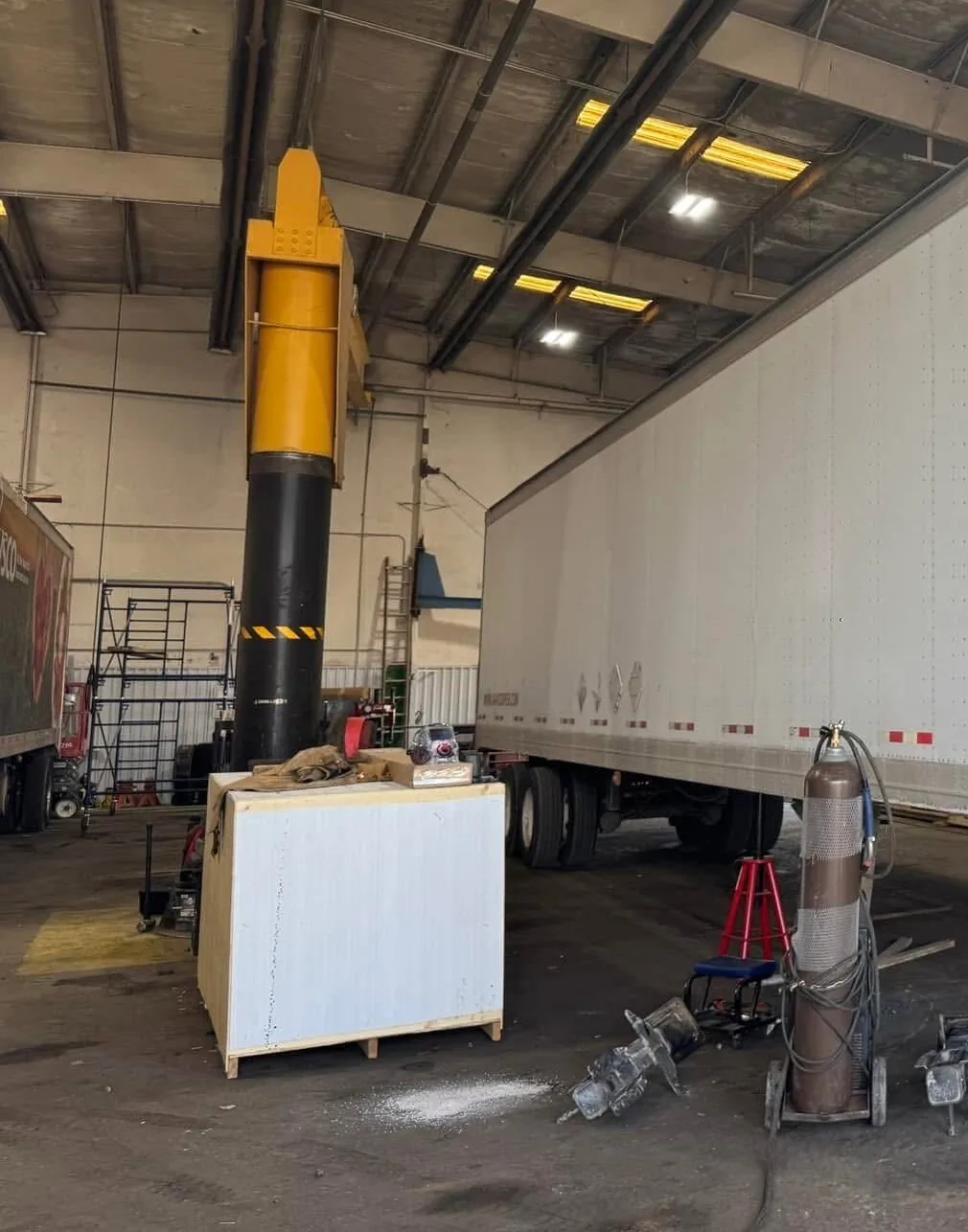 A trailer up on jack stands in Superior's shop bay on Bishop Lane, with the column lift and tool carts