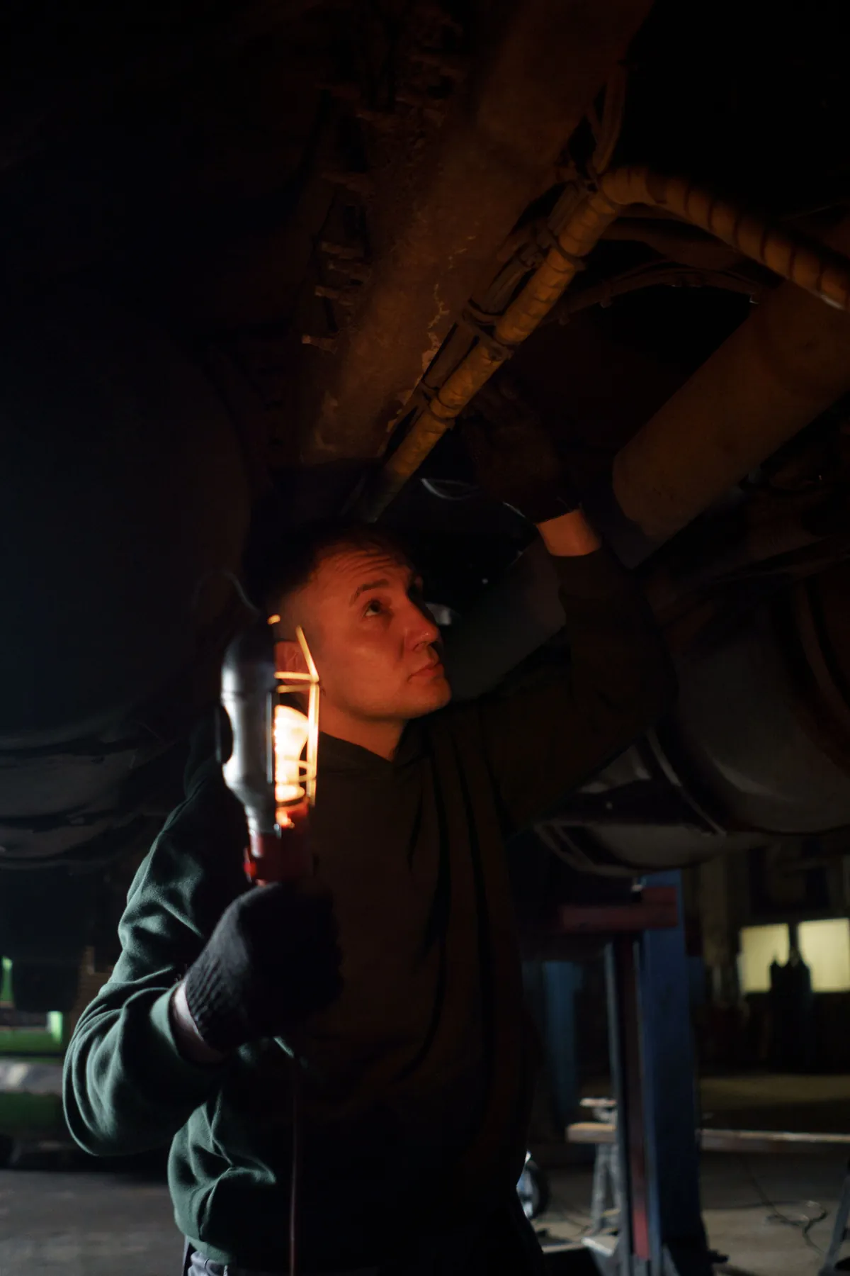 A technician checking the underside of a truck with a trouble light