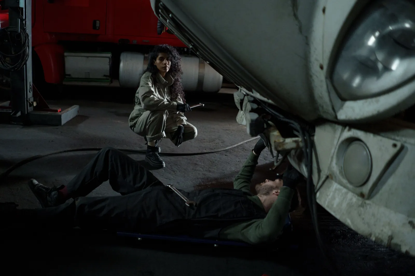 A technician on a creeper working under a truck